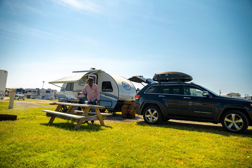 A small SUV with a travel trailer on a sunny RV site.
