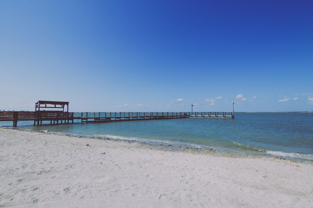 View of a pier on a sandy beach.