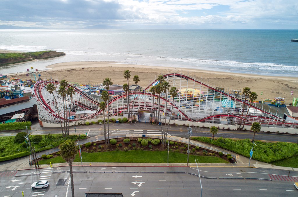 An aerial view of a roller coaster with the beach and ocean in the background.
