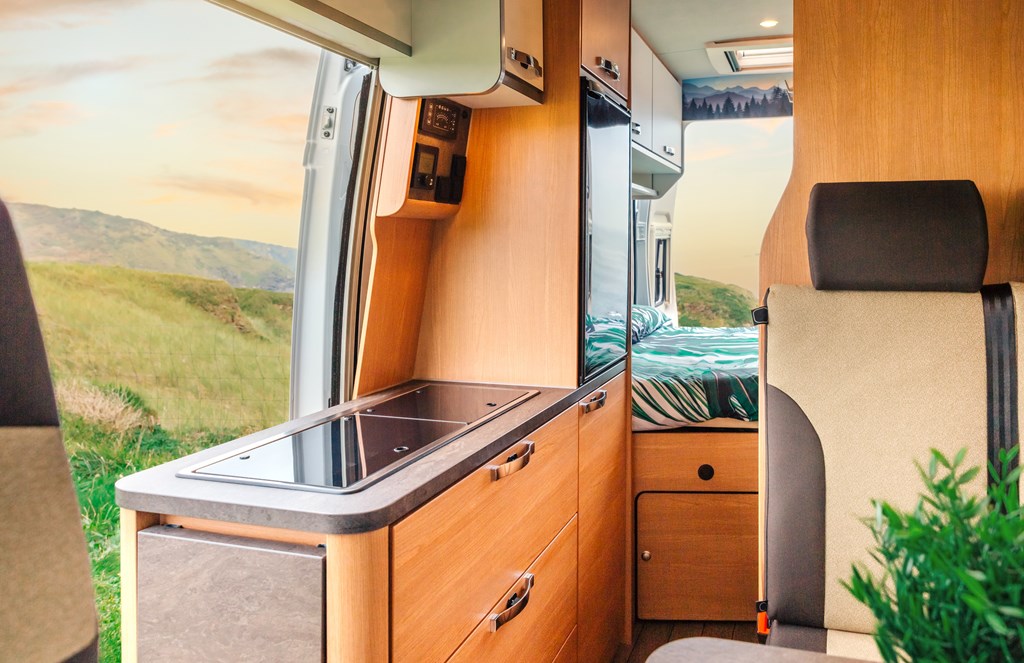 Interior of a camper van with kitchen and bed in the background.